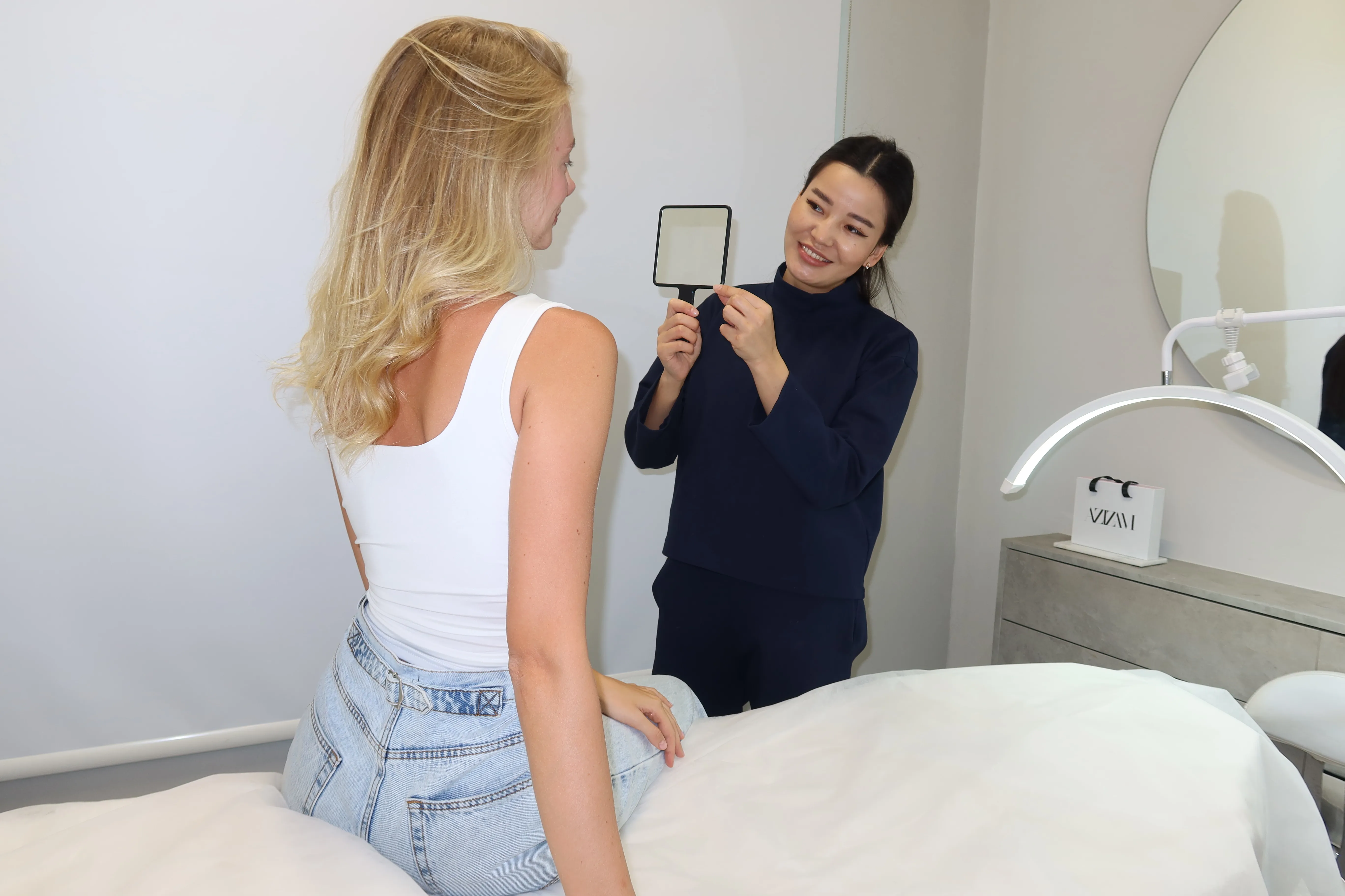 Azizam technician showing a client the final result in a hand mirror